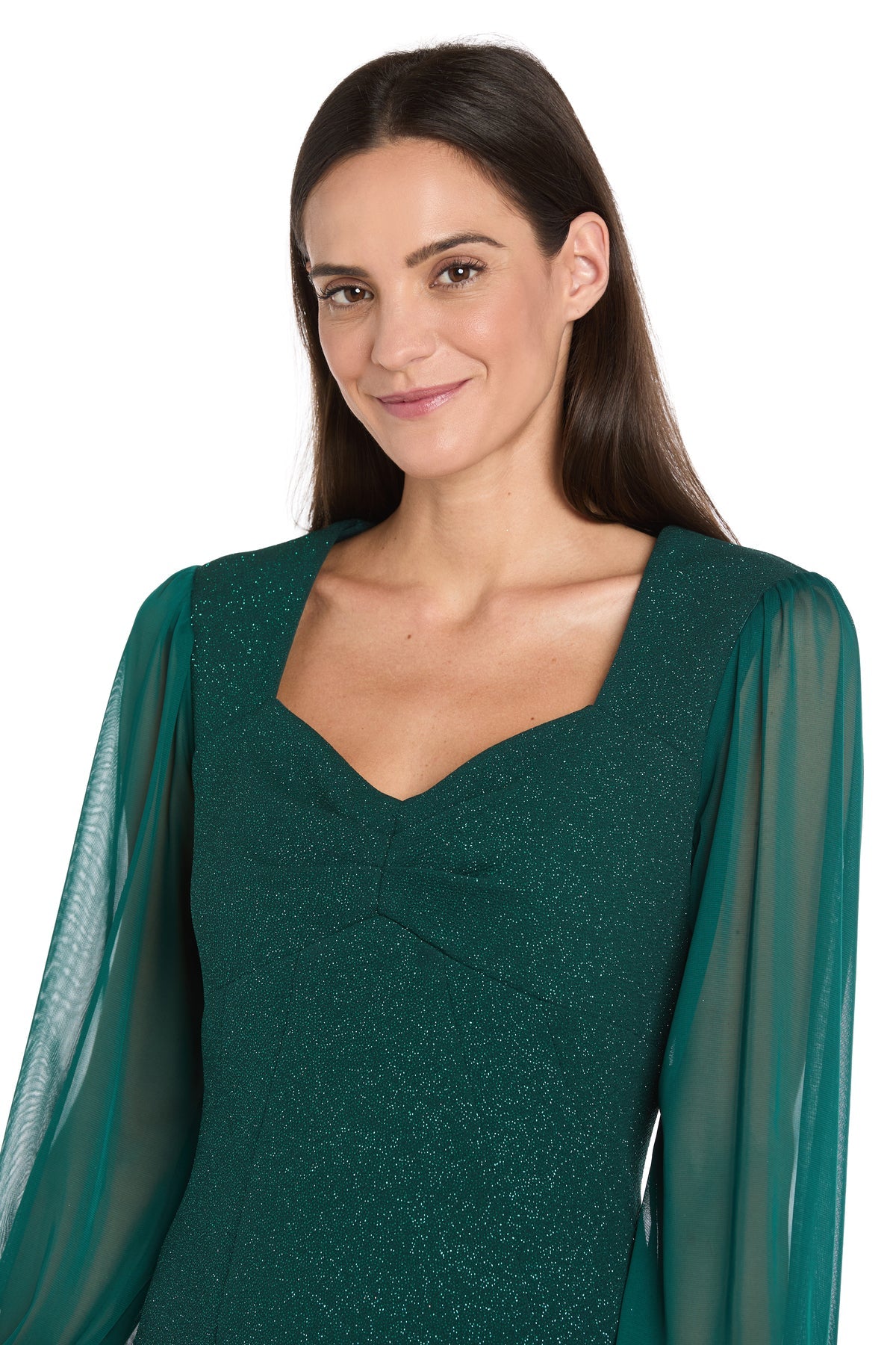 Woman wearing a green glitter dress with sheer sleeves on a white background